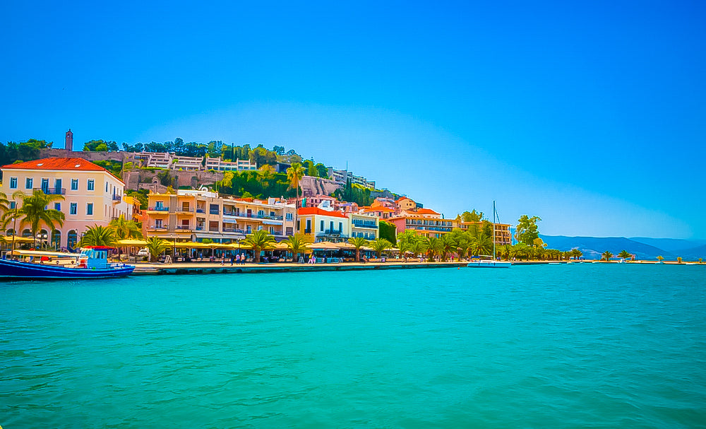 A scenic Greek seaside view with charming cafes and restaurants, showcasing the beauty of Greece, served by Royal Hellenic Transfers, a private minivan transfer service.