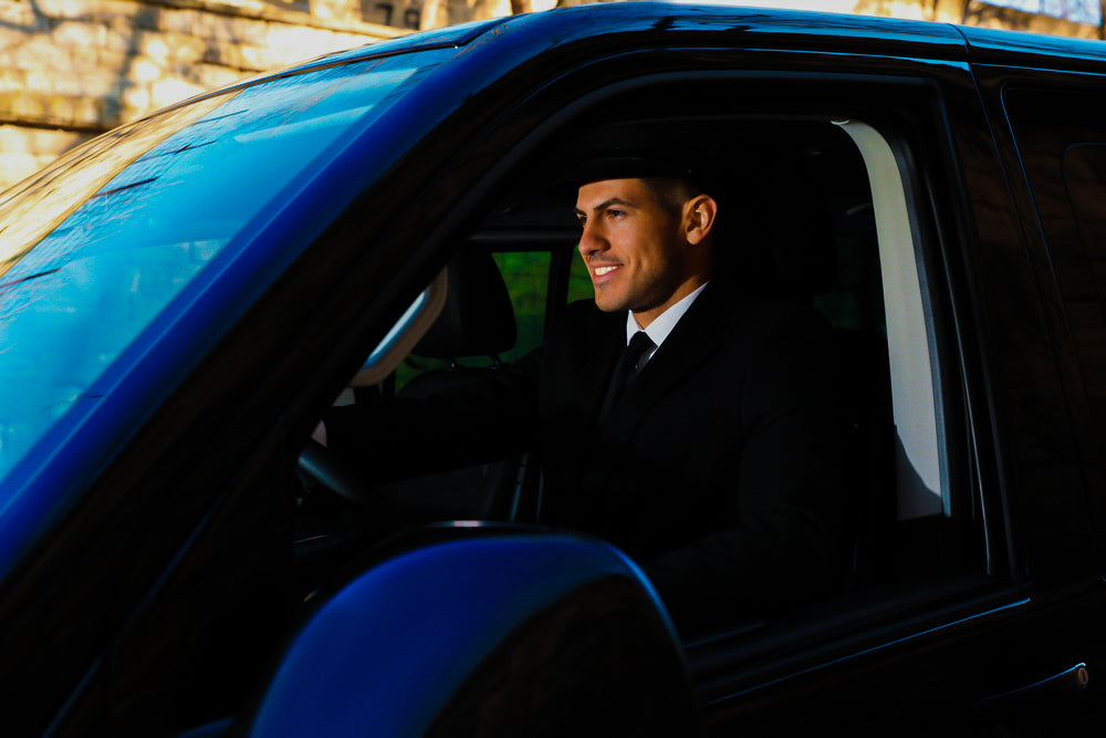 A smiling chauffeur drives a private minivan for Royal Hellenic Transfers, providing premium transfer services in Athens, Greece.